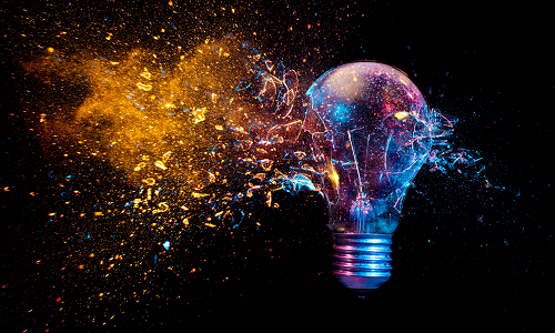 Exploding lightbulb, coloured light, black background Copyright: Shutterstock ID: 1717572952