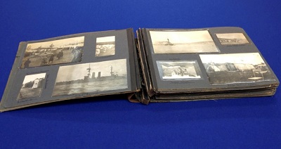 The album is opened at two pages containing a total of eight photographs variously showing nurses and navy ships.