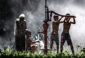 photo of boys and grandmother at a water pump in Ban Muang Kao, Thailand