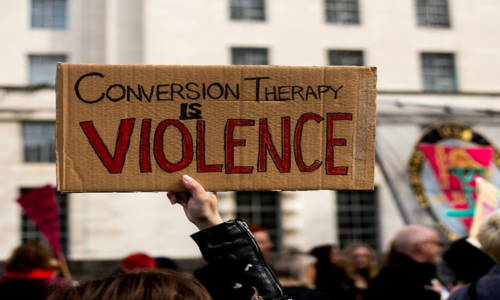 Someone holding a cardboard sign with the text 'Conversion Therapy is Violence'