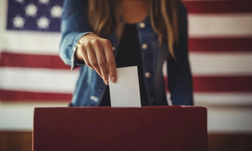 A woman holding their voting cards before dropping it into a ballet box 
