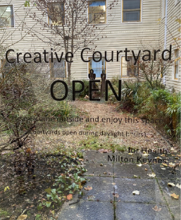 The words 'Creative Courtyard OPEN' as vinyl stickers on a glass looking out into a courtyard