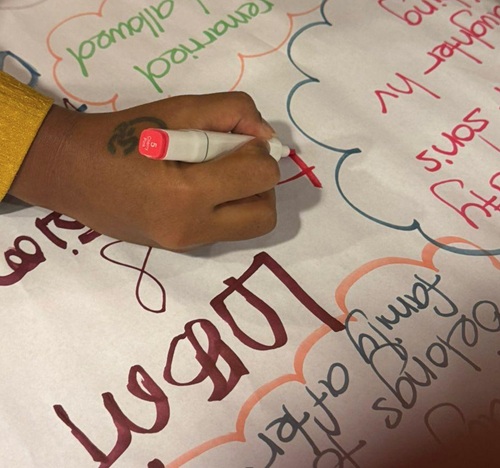A girl engaged in writing  during an activity discussing their household roles
