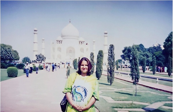 Shanthini, in a bright green t-shirt embossed with a blue and white design, in Delhi, standing in the grounds of the Taj Mahal