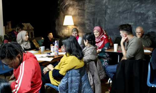 A group of people sat together listening to a female speaker, at a workshop event in Peterborough.