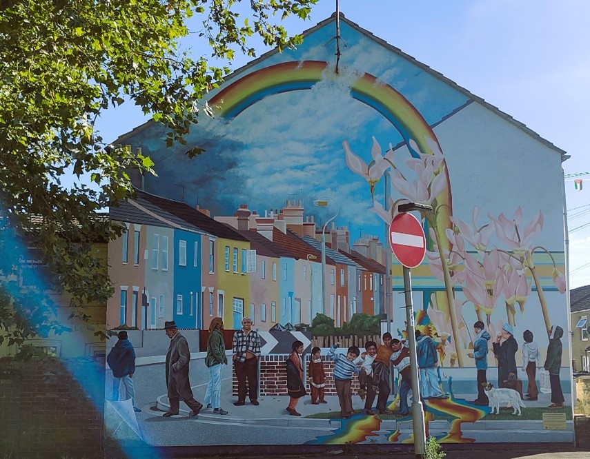 A colourful street mural in Peterborough, called the Link Road Mural, with a group of people on a building