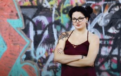 A woman standing in front of a graffiti-covered wall