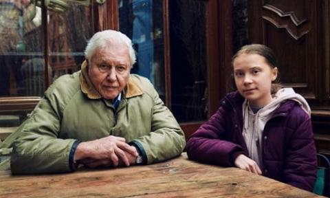 Sir David Attenborough and Greta Thunberg sit side by side at a table (photo credit: Alex Board)