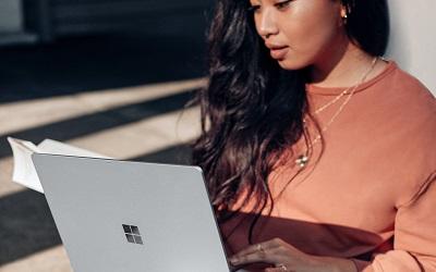 A female with long dark hair using a laptop