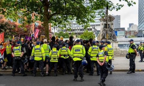 groups of police and protesters walking down a street in Manchester 2024