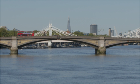 Red London Bus driving over Southwark Bridge with Millennium bridge in the background