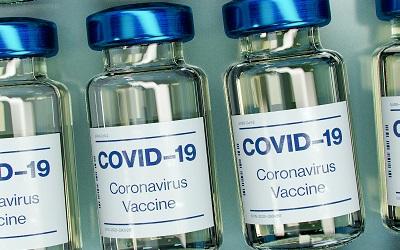Photo by Daniel Schludi on Unsplash - images shows a row of COVID-19 vaccines in small blue bottles