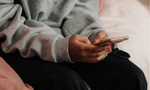 A close-up of a teenage girl’s hands, holding her smartphone