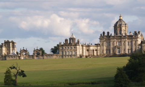 View of Castle Howard exterior north front, main house crowned by a dome, with west wing and separate kitchen block, in a grassy landscape.