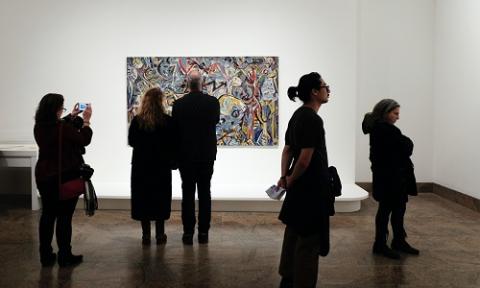 A small crowd of people observing a piece of art in a gallery