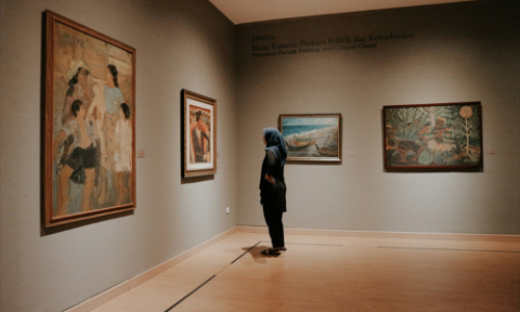 A woman wearing a hijab, looking at a painting in the National Gallery, Indonesia