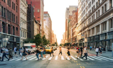 People walk across a marked road crossing in between high-rise buildings in New York city 