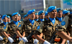 Army men wearing camouflage with blue hats, undershirts and white gloves, marching